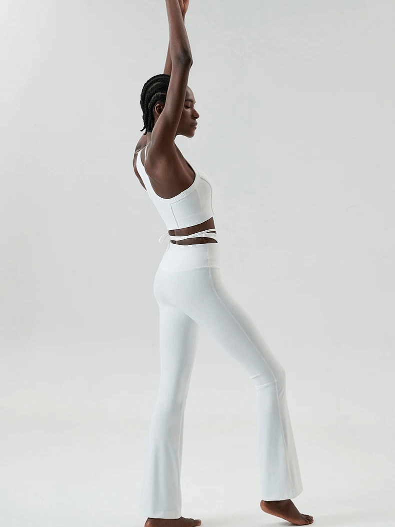 Woman in sleek athletic yoga pants and top set performing a graceful stretch, showcasing freedom of movement and style for fitness activities.